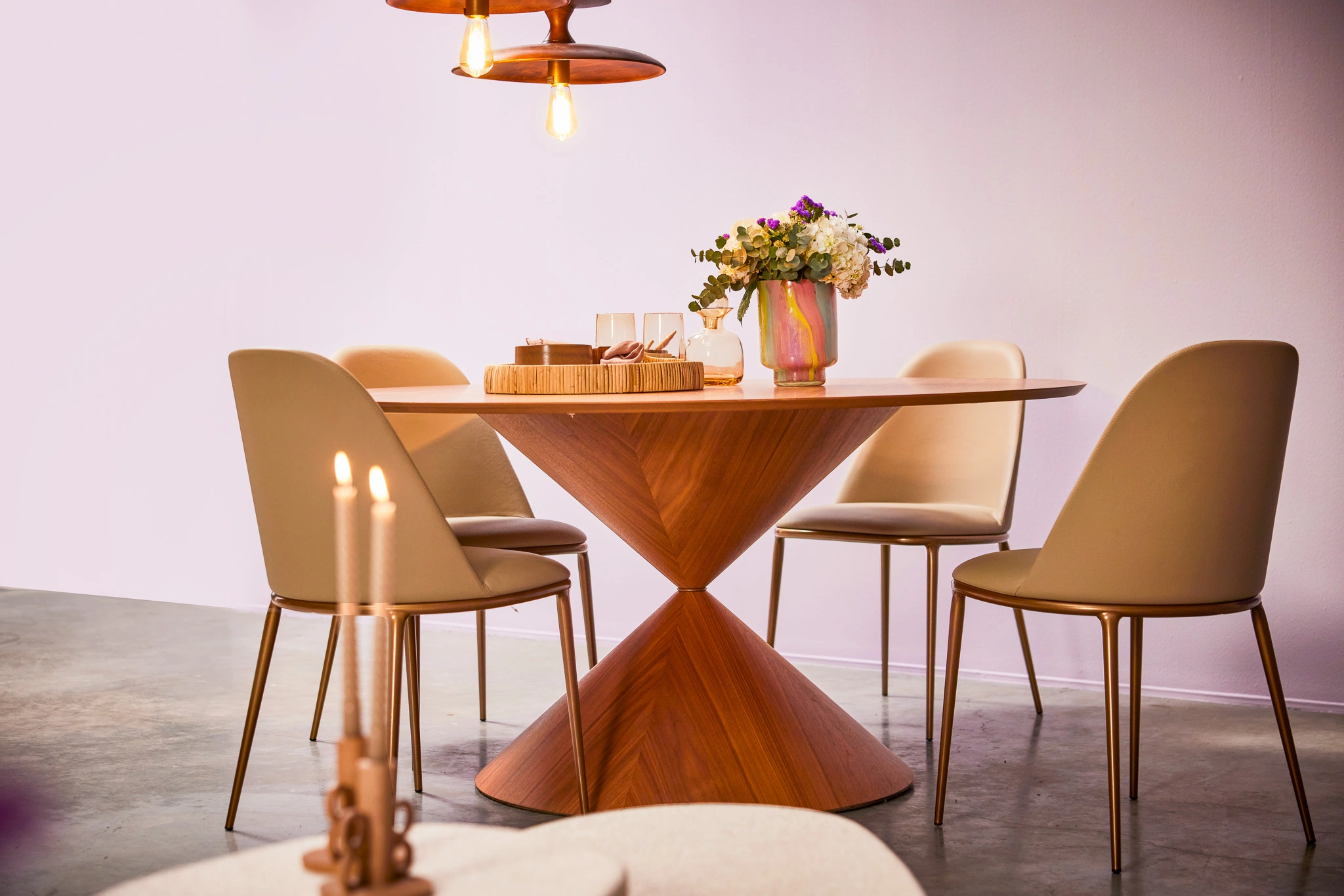 Table design moderne en bois avec des chaises élégantes, décorée d'un vase de fleurs et de bougies. Ambiance chic et conviviale pour la salle à manger.