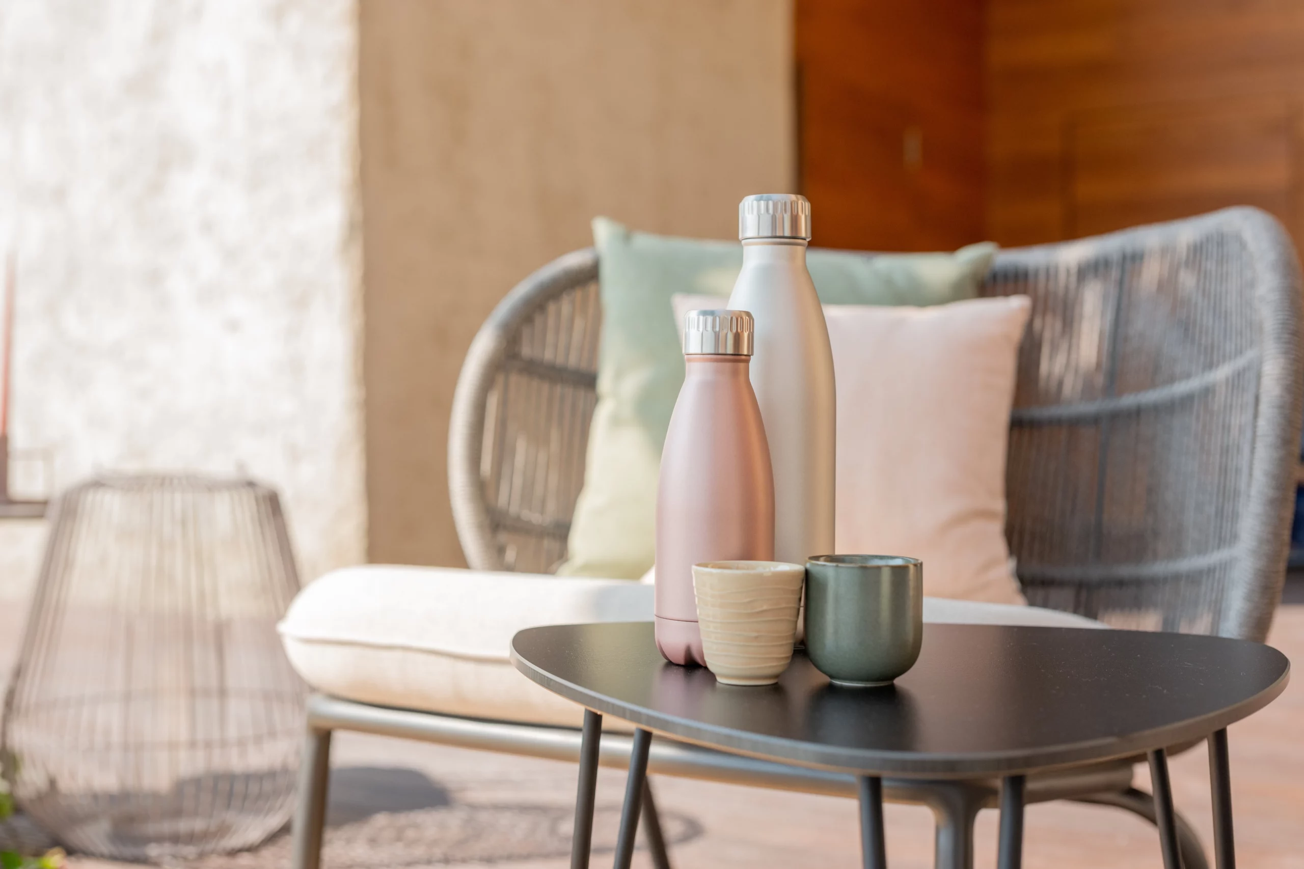 Table d'appoint design sur terrasse avec thermos élégants et tasses modernes, parfaite pour un moment de détente extérieur dans un cadre stylé et convivial.